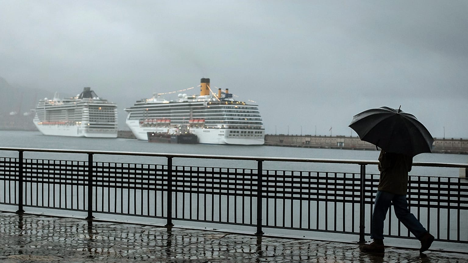 ARCHIVO: Un hombre sostiene un paraguas mientras camina junto al puerto marítimo durante una fuerte lluvia en Santa Cruz de Tenerife, Islas Canarias, España, 2013.