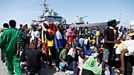 Migrants prepare to board an Italian Navy ship to be taken away from Lampedusa Island after being rescued at sea