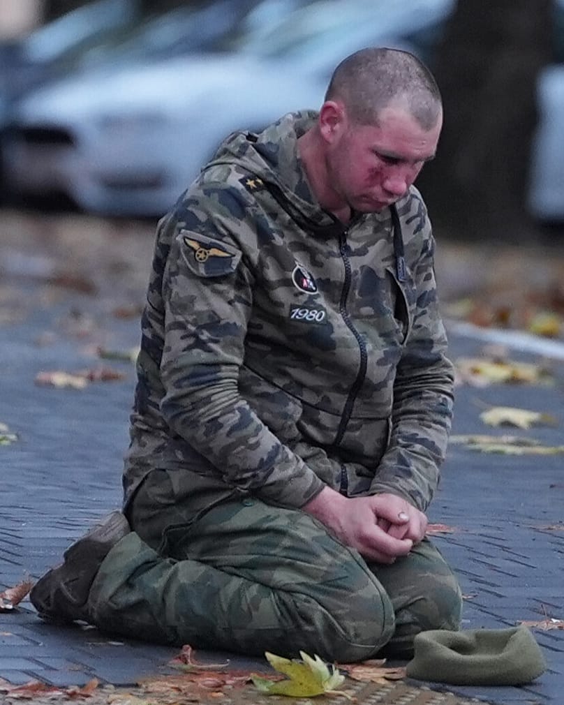 Ein traumatisierter ukrainischer Soldat kniet auf der Straße. 
