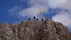Menschen posieren am Gipfelkreuz der Zugspitze, Deutschlands höchstem Berg nahe Garmisch-Partenkirchen. 2962 Meter hoch.