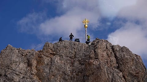 Des personnes posent à la croix sommitale de la plus haute montagne d'Allemagne, la Zugspitze (2 962 mètres), près de Garmisch-Partenkirchen