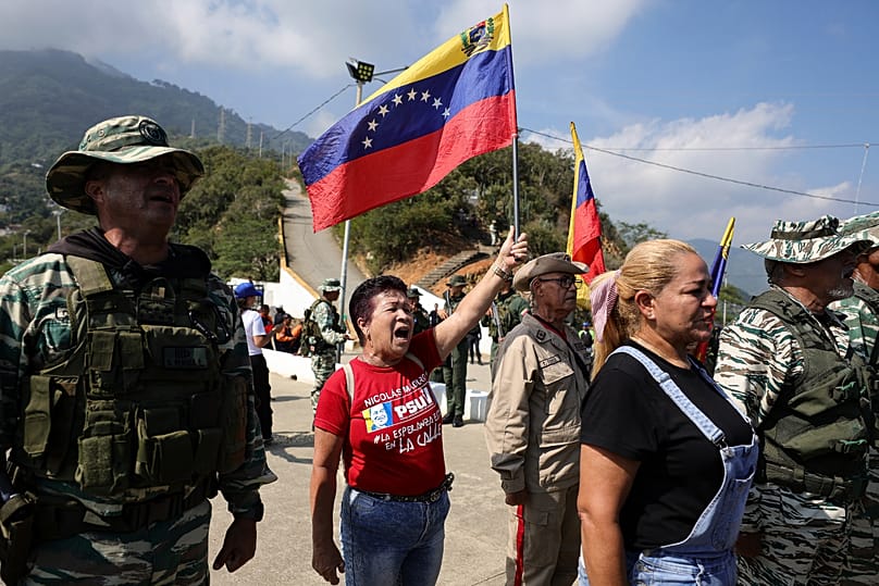 A woman holds up a national flag during military exercises in La Guaira, Venezuela, Saturday, Sept. 20, 2025.
