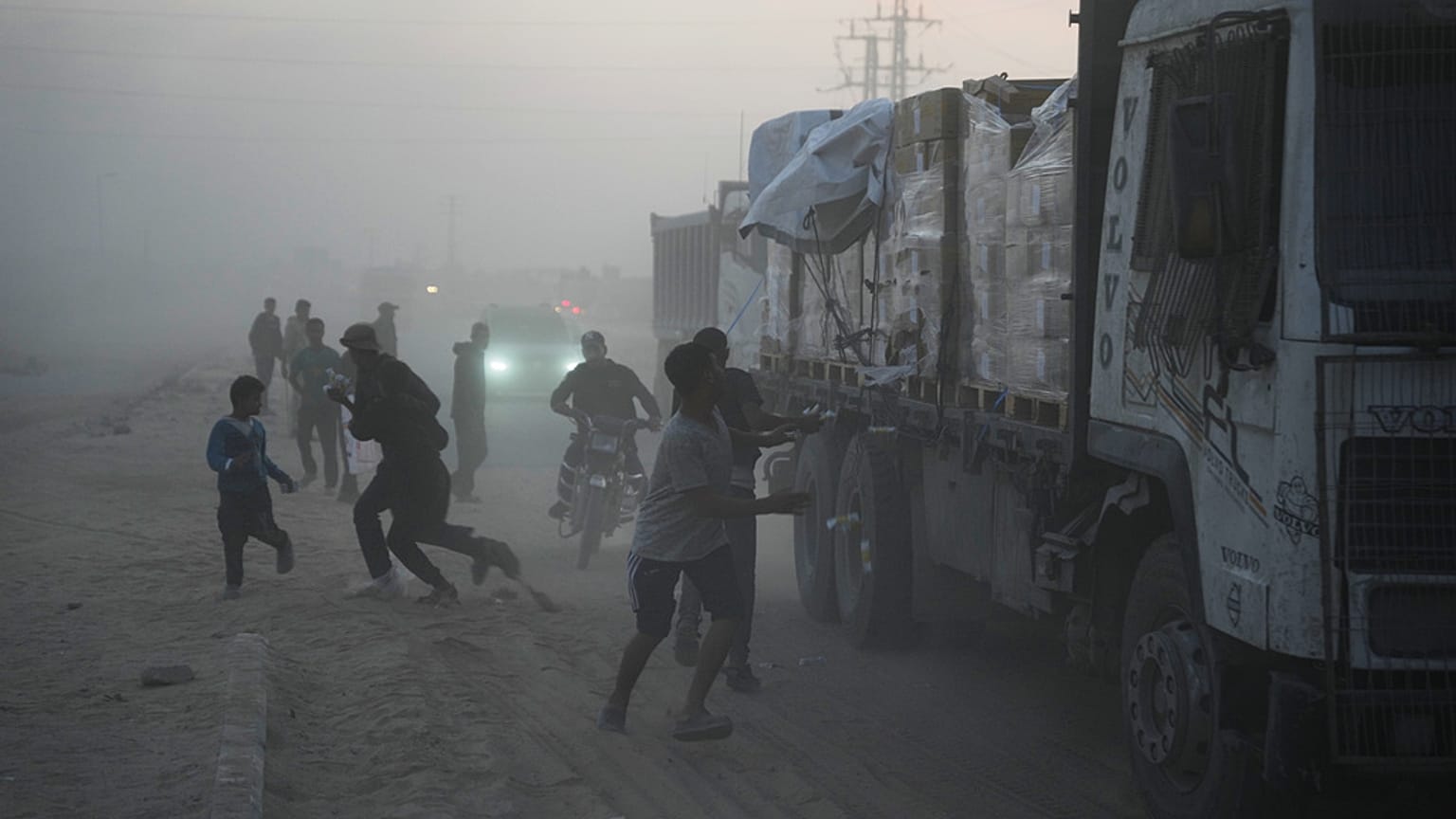 فلسطينيون يسارعون نحو الشاحنات التي تحمل مساعدات من برنامج الغذاء العالمي أثناء مرورها بدير البلح في وسط غزة، السبت 8 نوفمبر/تشرين الثاني 2025.