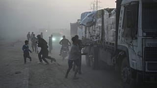 فلسطينيون يسارعون نحو الشاحنات التي تحمل مساعدات من برنامج الغذاء العالمي أثناء مرورها بدير البلح في وسط غزة، السبت 8 نوفمبر/تشرين الثاني 2025.