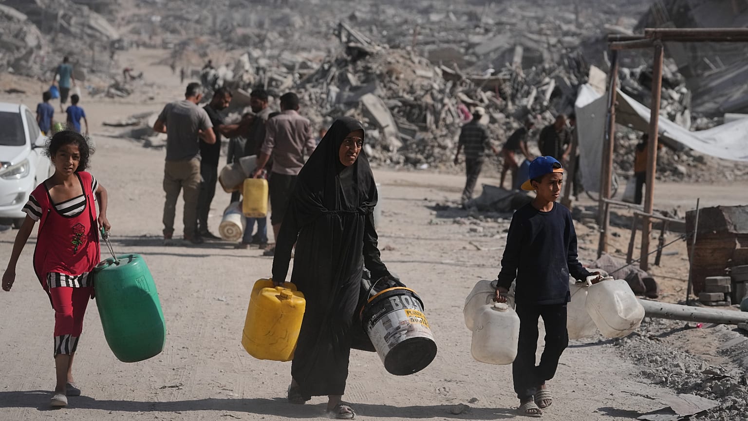 فلسطينيون يحملون عبوات مياه لجمعها من شاحنة وسط الدمار الذي خلّفته الحرب الإسرائيلية في مدينة غزة، الخميس، 16 أكتوبر/تشرين الأول 2025.