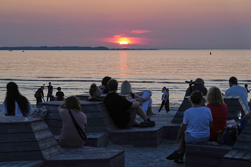 People watch the sunset at the embankment of the Baltic sea in Tallinn, Estonia, Thursday, July 24, 2025.
