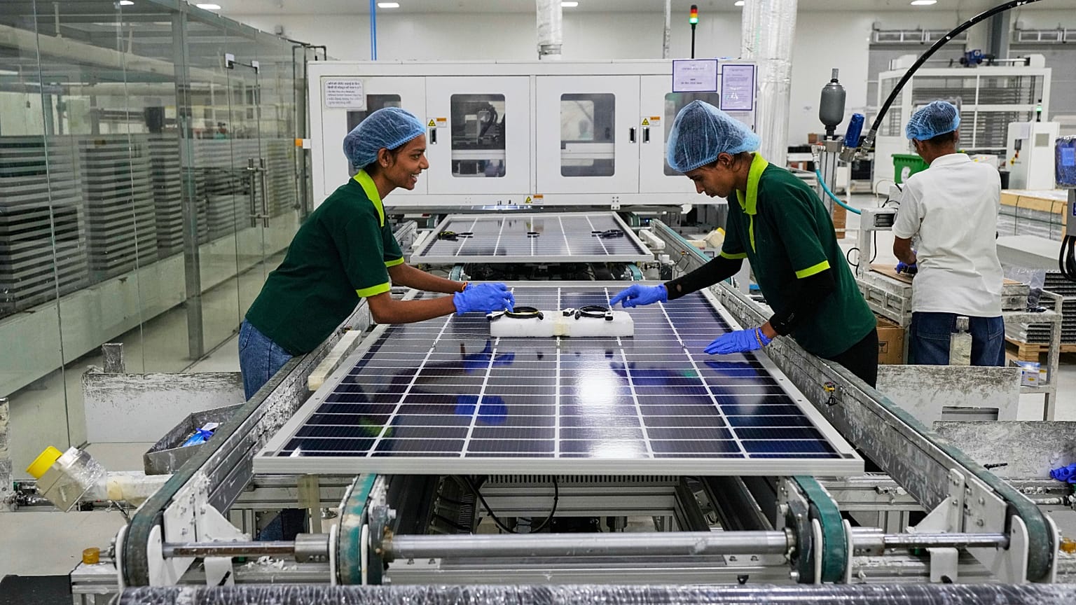 Workers put switches and connectors on solar panels after they come out of automated framing at a ReNew solar panel manufacturing plant on the outskirts of Jaipur, India.