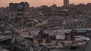 فلسطينيون يسيرون بين أنقاض حي الشيخ رضوان في غزة بعد الهجمات الجوية والبرية الإسرائيلية، 11 نوفمبر 2025.