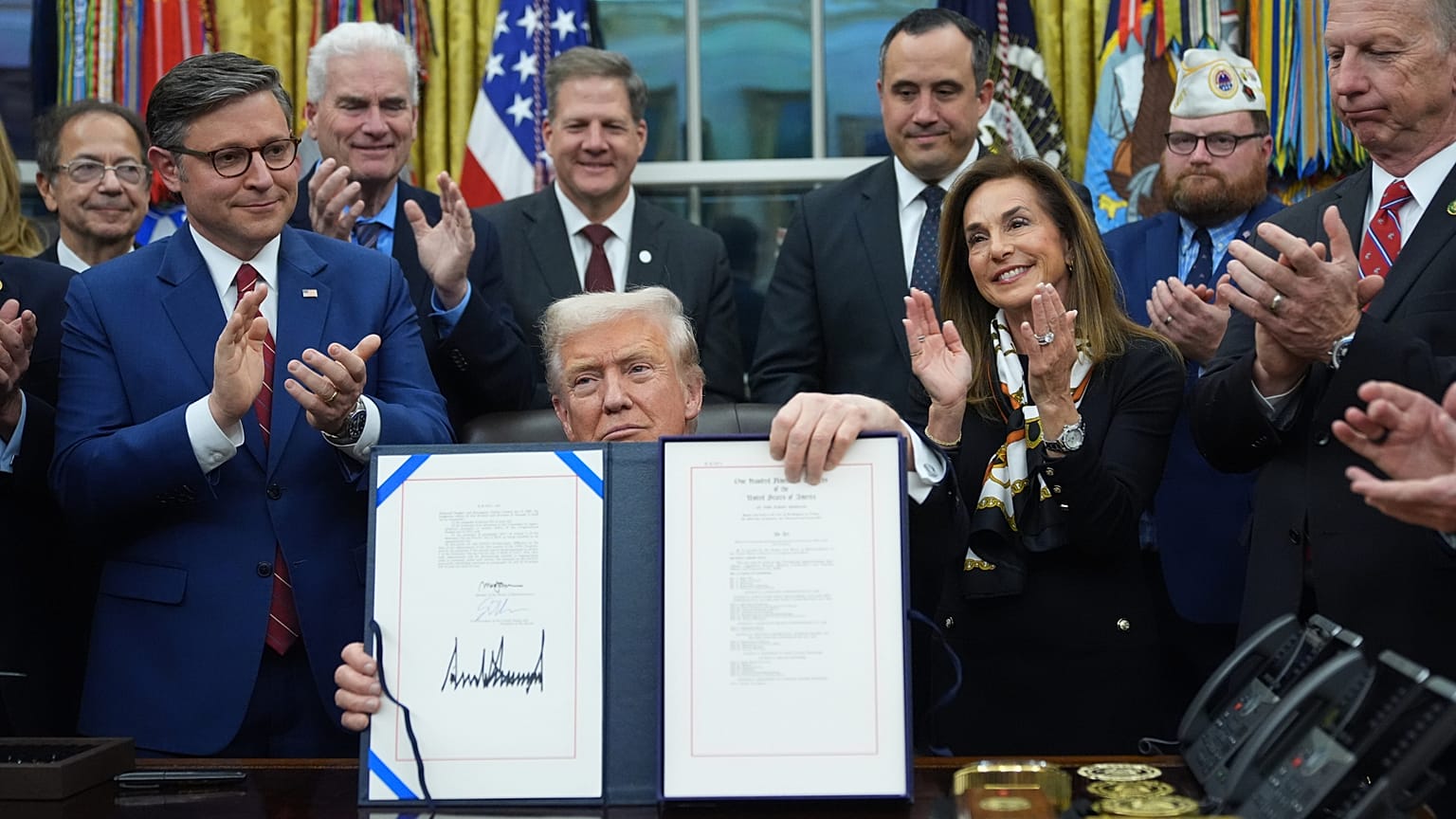 President Donald Trump displays the signed funding bill to reopen the government, in the Oval Office of the White House, Wednesday, Nov. 12, 2025, in Washington. 