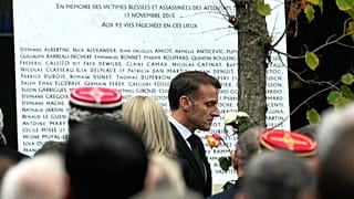 Le président français Emmanuel Macron passe devant la plaque gravée des noms des victimes devant la salle de concert du Bataclan.