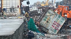 Un homme saute à côté d'un conteneur renversé par le typhon Fung-wong, le lundi 10 novembre 2025, à Navotas, aux Philippines