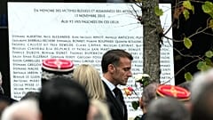 Presidente francês Emmanuel Macron passa junto da placa gravada com os nomes das vítimas à porta da sala de concertos Bataclan.