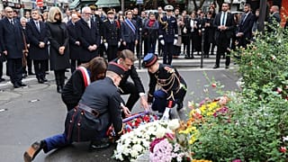 الرئيس الفرنسي إيمانويل ماكرون (في الوسط) يضع إكليلاً من الزهور على شرف الضحايا قرب مقهى "لوبون بيير"، الخميس 13 نوفمبر/تشرين الثاني 2025 في باريس، ضمن مراسم إحياء الذكرى العا