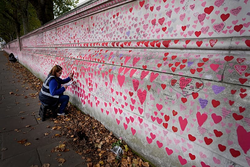 A volunteer writes inscriptions on the COVID-19 memorial wall in London, 15 October, 2021