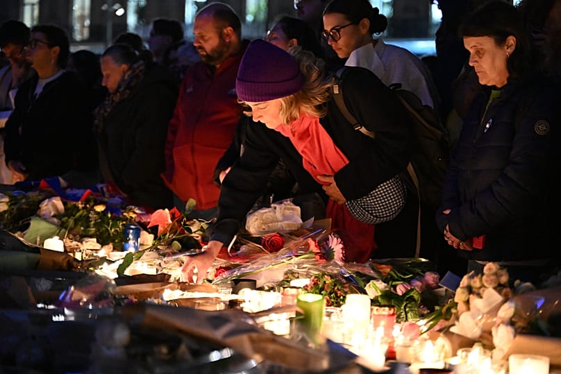 A woman places a candle at the Place de la Republique as Paris is marking the 10th anniversary of terrorist attacks Thursday, Nov. 13, 2025 in Paris. 