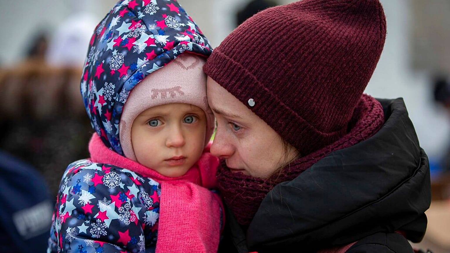 صورة تعبيرية لأم وطفلها، هاربان من أوكرانيا، ينتظران ركوب حافلة عند معبر ميديكا الحدودي
