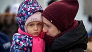 صورة تعبيرية لأم وطفلها، هاربان من أوكرانيا، ينتظران ركوب حافلة عند معبر ميديكا الحدودي