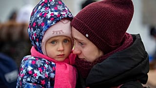 صورة تعبيرية لأم وطفلها، هاربان من أوكرانيا، ينتظران ركوب حافلة عند معبر ميديكا الحدودي