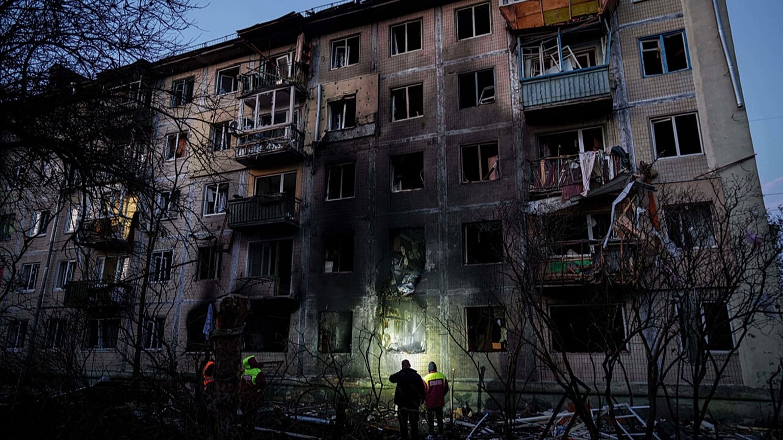 Municipal workers look at a residential building damaged after a Russian attack on Kyiv, Ukraine, on Friday, Nov. 14, 2025.