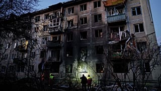 Municipal workers look at a residential building damaged after a Russian attack on Kyiv, Ukraine, on Friday, Nov. 14, 2025.