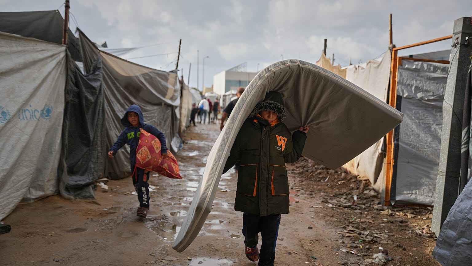 يسير فلسطيني بين الخيام بعد هطول الأمطار في مخيم مؤقت بمدينة دير البلح وسط قطاع غزة، يوم الجمعة 14 نوفمبر 2025.