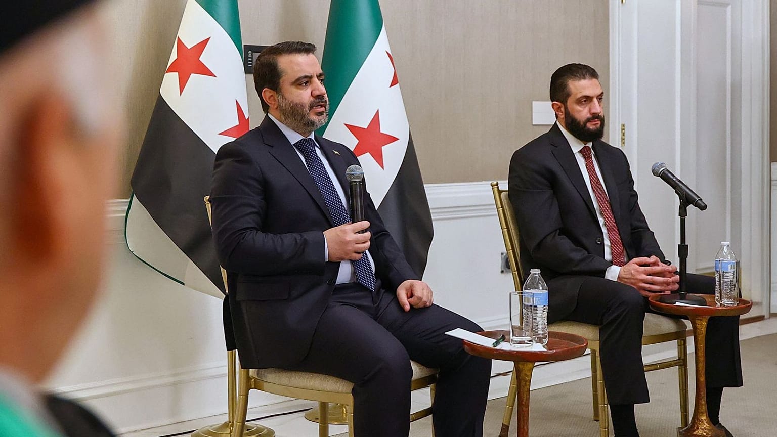 احمد الشرع، رئیس جمهور سوریه، در حال گوش دادن به سخنان اسعد الشیبانی، وزیر امور خارجه سوریه، در دیدار با نمایندگان سازمان‌های سوری-آمریکایی در واشنگتن، شنبه، ۸ نوامبر۲۰۲۵