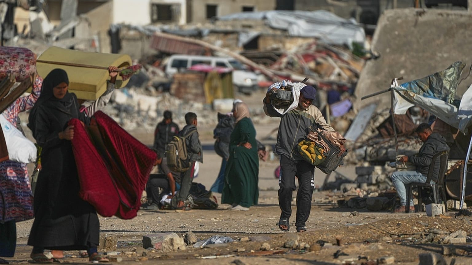 A Palestinian man carries bags of firewood after collecting them from the rubbish in Khan Younis, southern Gaza Strip, on Saturday, Nov. 15, 2025. 