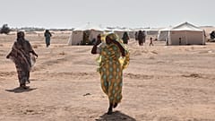 النساء السودانيات النازحات من الفاشر، عاصمة شمال دارفور، وغيرها من المناطق المتأثرة بالنزاع، يسيرن عبر مخيم الإفاض الجديد في منطقة الدبة، ولاية الشمالية،