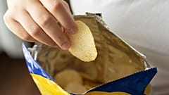 Eine Person hält eine Tüte Chips.