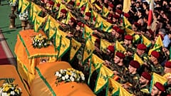 يرفع عناصر حزب الله راياتهم إلى جانب خمسة نعوش في بلدة النبطية جنوبي لبنان، يوم الأحد، 2 تشرين الثاني/نوفمبر 2025.