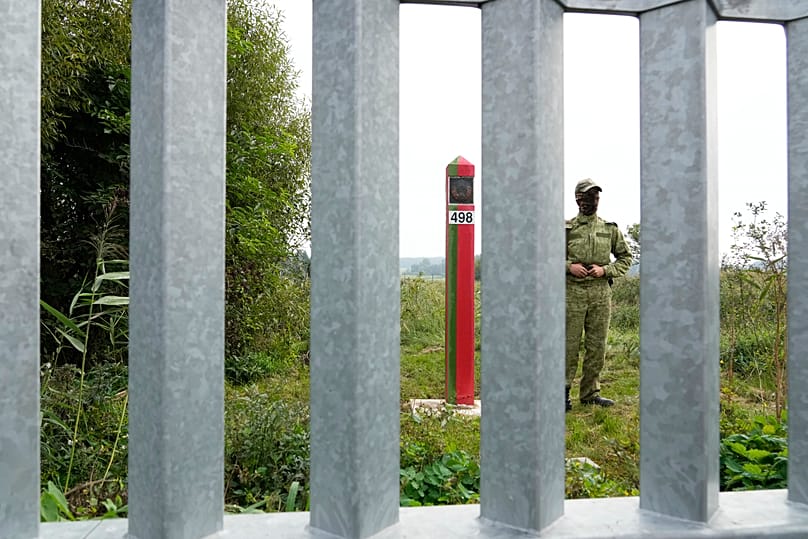 A Belarusian border guard is seen behind a fence before the visit of Polish Prime Minister Donald Tusk on the border with Poland, 31 August, 2025