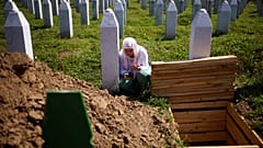 امرأة بوسنية مسلمة تصلّي قرب قبر أحد أقاربها من ضحايا إبادة سربرنيتسا، البوسنة، في 11 يوليو 2024، خلال إحياء الذكرى التاسعة والعشرين للمجزرة.