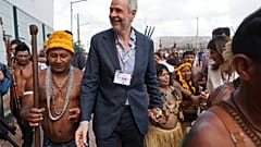 André Corrêa do Lago, Präsident der COP30, in der Mitte, geht am 14. November 2025 mit einer Gruppe vor dem Tagungsort in Belém. Er hält die Hand einer indigenen Frau.