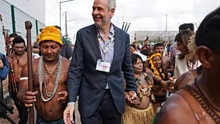 André Corrêa do Lago, presidente de la COP30, sujeta la mano de una mujer indígena mientras camina con un grupo fuera de la sede, el 14 de noviembre de 2025 en Belém, Brasil