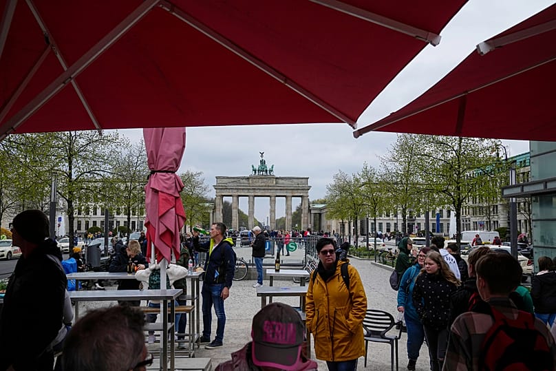 FILE: People have a meal in an outdoor cafe, with the Brandenburg Gate in the background, in Berlin, Germany, Thursday, 21 April 2022
