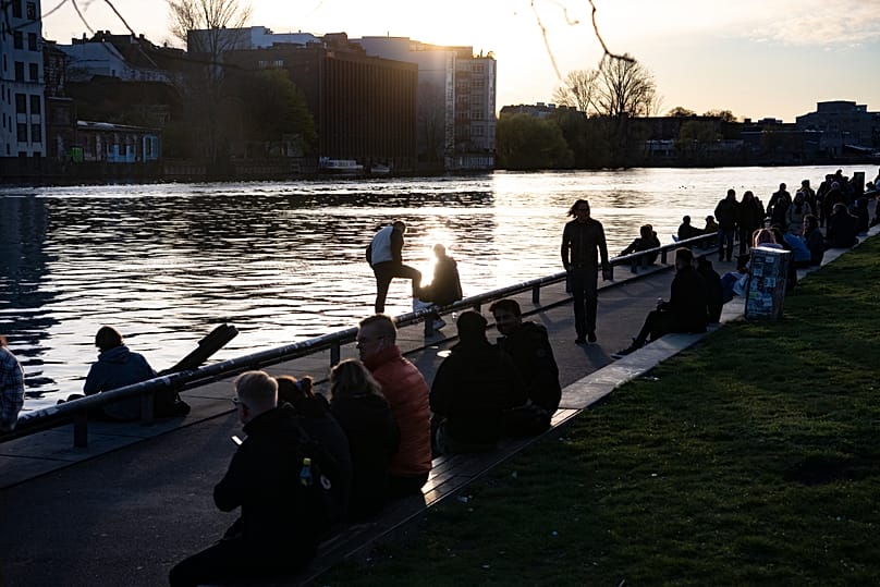 FILE: People watch the sunset from the banks of the Spree at the East Side Gallery in Berlin, 16 April 2022