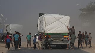  فلسطينيون يهرعون نحو شاحنات المساعدات لدى مرورها في دير البلح وسط غزة، الأحد 9 تشرين الثاني 2025.