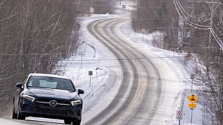 Trees are covered with snow and ice as cars drive on a road in the forests of the Taunus region in Frankfurt