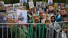 Angehörige mit Fotos ihrer vermissten Verwandten begrüßen Rückkehrer beim Kriegsgefangenenaustausch in der Region Tschernihiw, 20. Oktober 2025