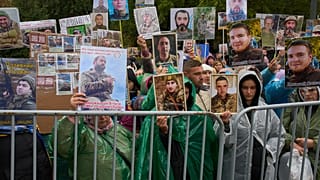 People hold photos of their missed relatives as Ukrainian soldiers return from captivity during a POW exchange between Russia and Ukraine in Chernyhiv region, Ukraine, Oct, 20