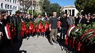 People raise their arms as they lay a wreath at a monument honouring students killed in the 1973 pro-democracy uprising