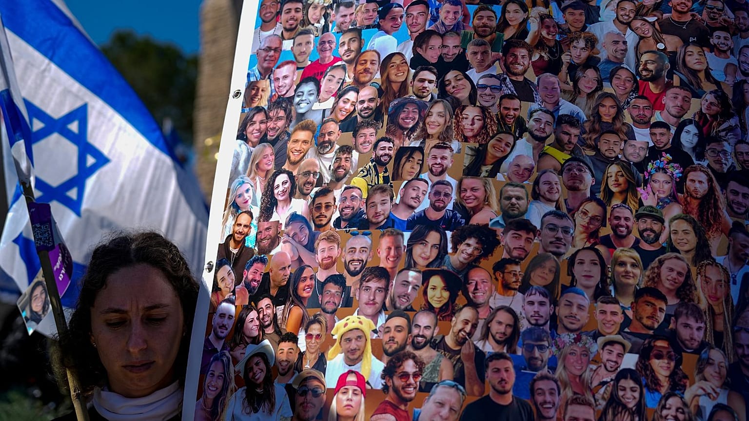 زنی اسرائیلی که تصویر قربانیان حمله هفت اکتبر حماس را در دست دارد