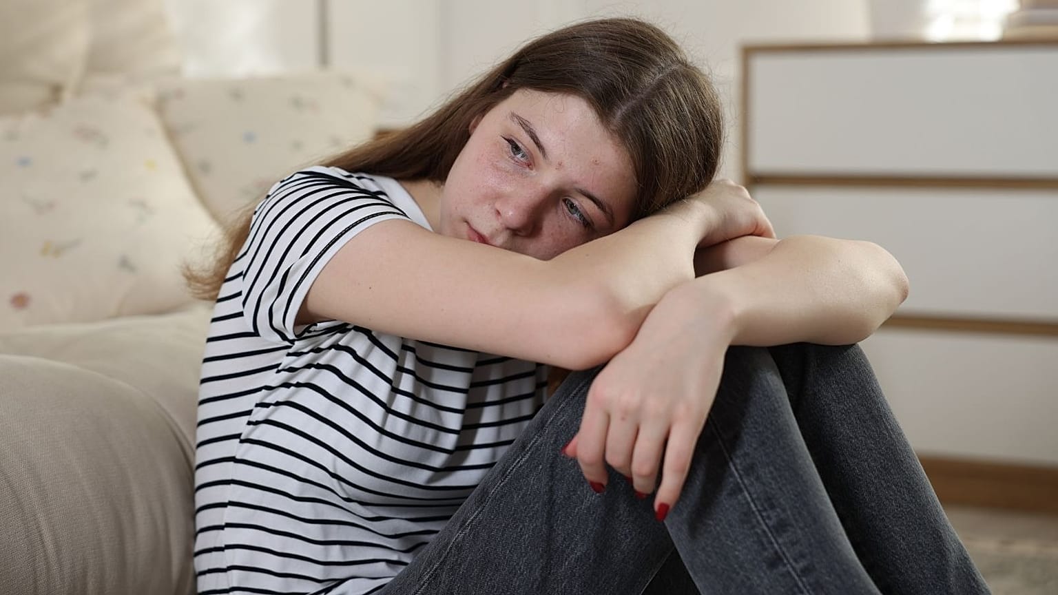 Un'adolescente triste guarda fuori dall'inquadratura.