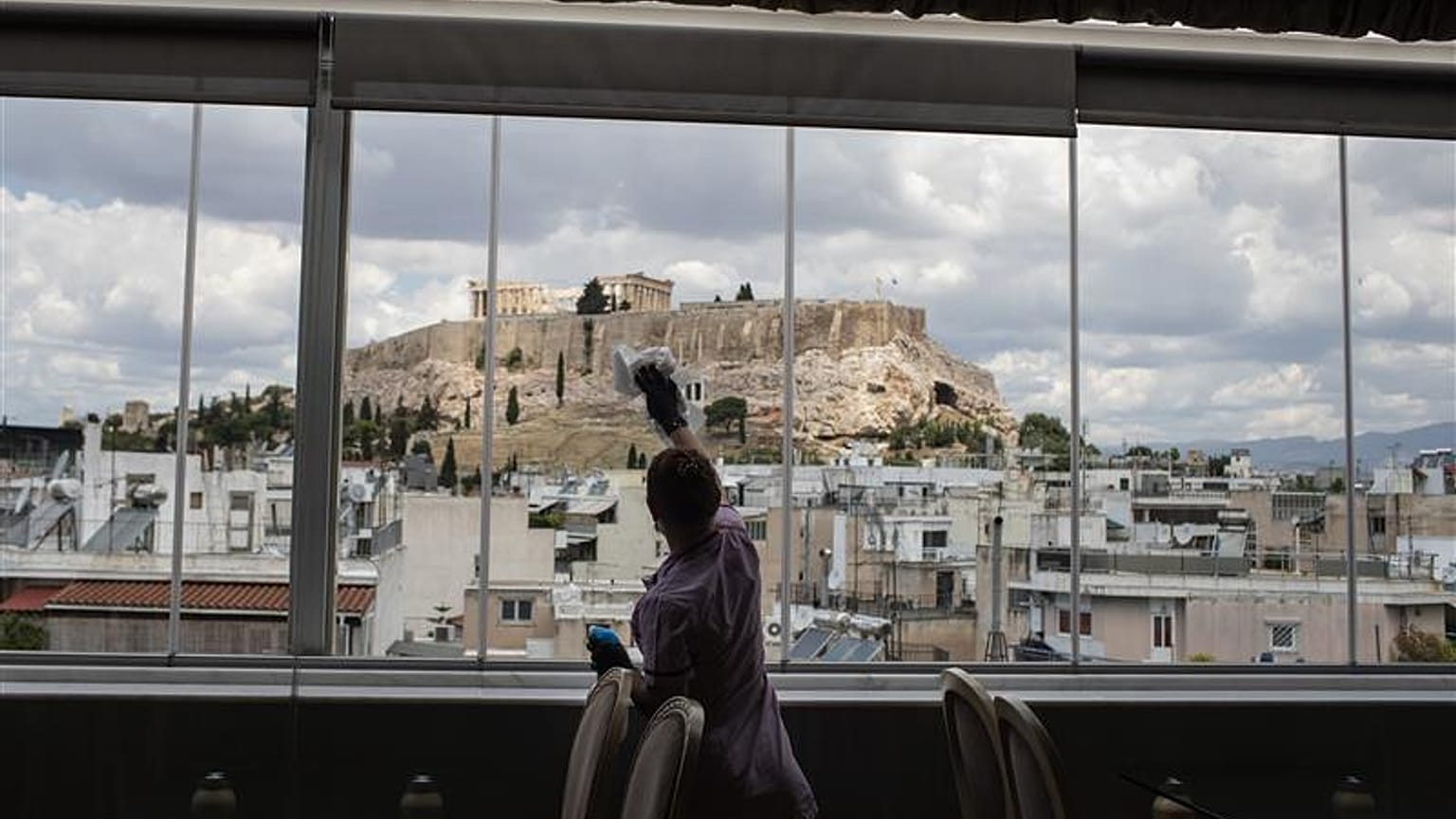 Hotel worker Mailinda Kaci cleans the windows in a restaurant area at the Acropolian Spirit Hotel in central Athens.l