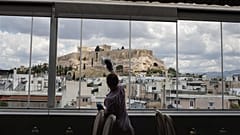 Die Hotelangestellte Mailinda Kaci putzt die Fenster im Restaurantbereich des Acropolian Spirit Hotels im Zentrum Athens.l