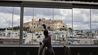 L'impiegata dell'hotel Mailinda Kaci pulisce le finestre dell'area ristorante dell'Acropolian Spirit Hotel, nel centro di Atene.l