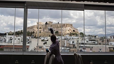 Hotel worker Mailinda Kaci cleans the windows in a restaurant area at the Acropolian Spirit Hotel in central Athens.l