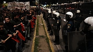 A destra, la polizia greca mette in sicurezza il perimetro dell'ambasciata Usa durante una manifestazione per il 52° anniversario della rivolta studentesca del 1973.