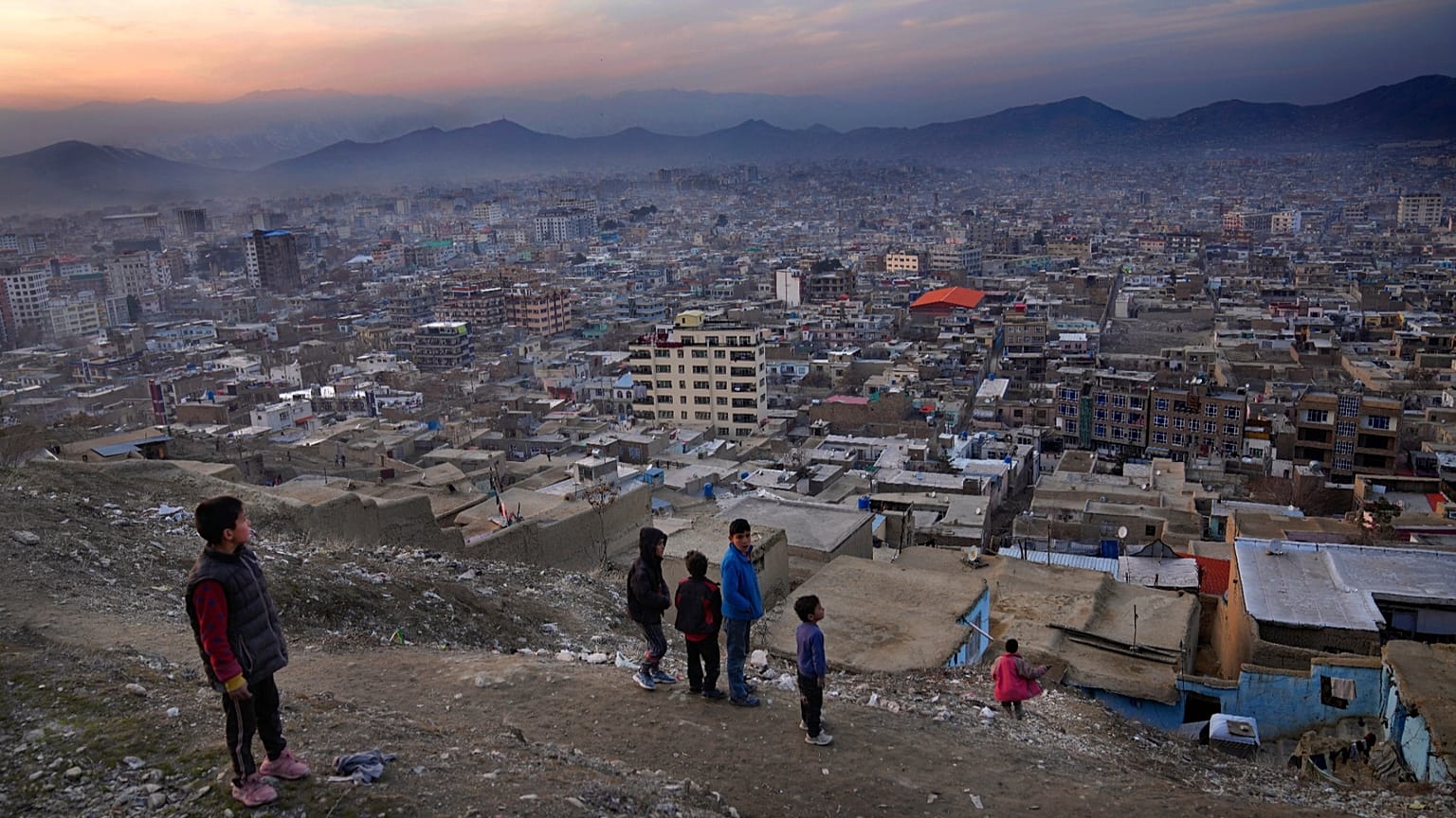 FILE: A boy flies a kite on a hilltop overlooking Kabul, 27 February 2022
