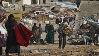 Filistinli bir adam, Gazze Şeridi'nin güneyindeki Han Yunus'ta çöplerden topladığı torbaları taşıyor, 15 Kasım 2025.